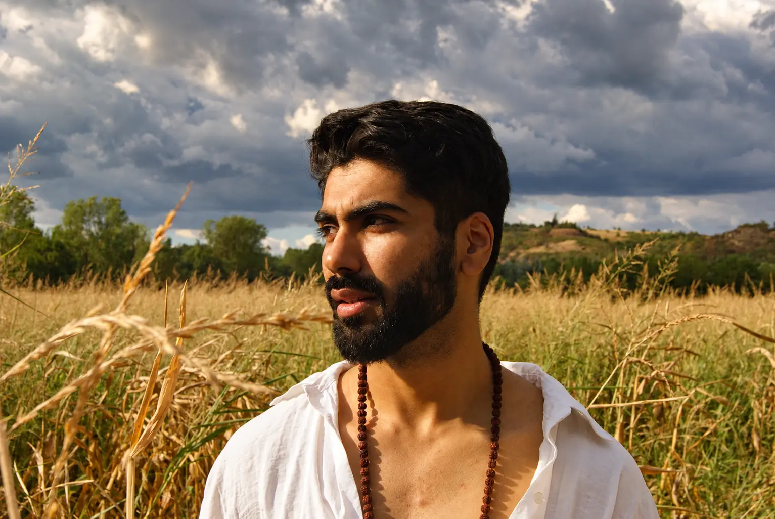 Archival portrait of Harshit Dixit in a field beneath a dramatic sky