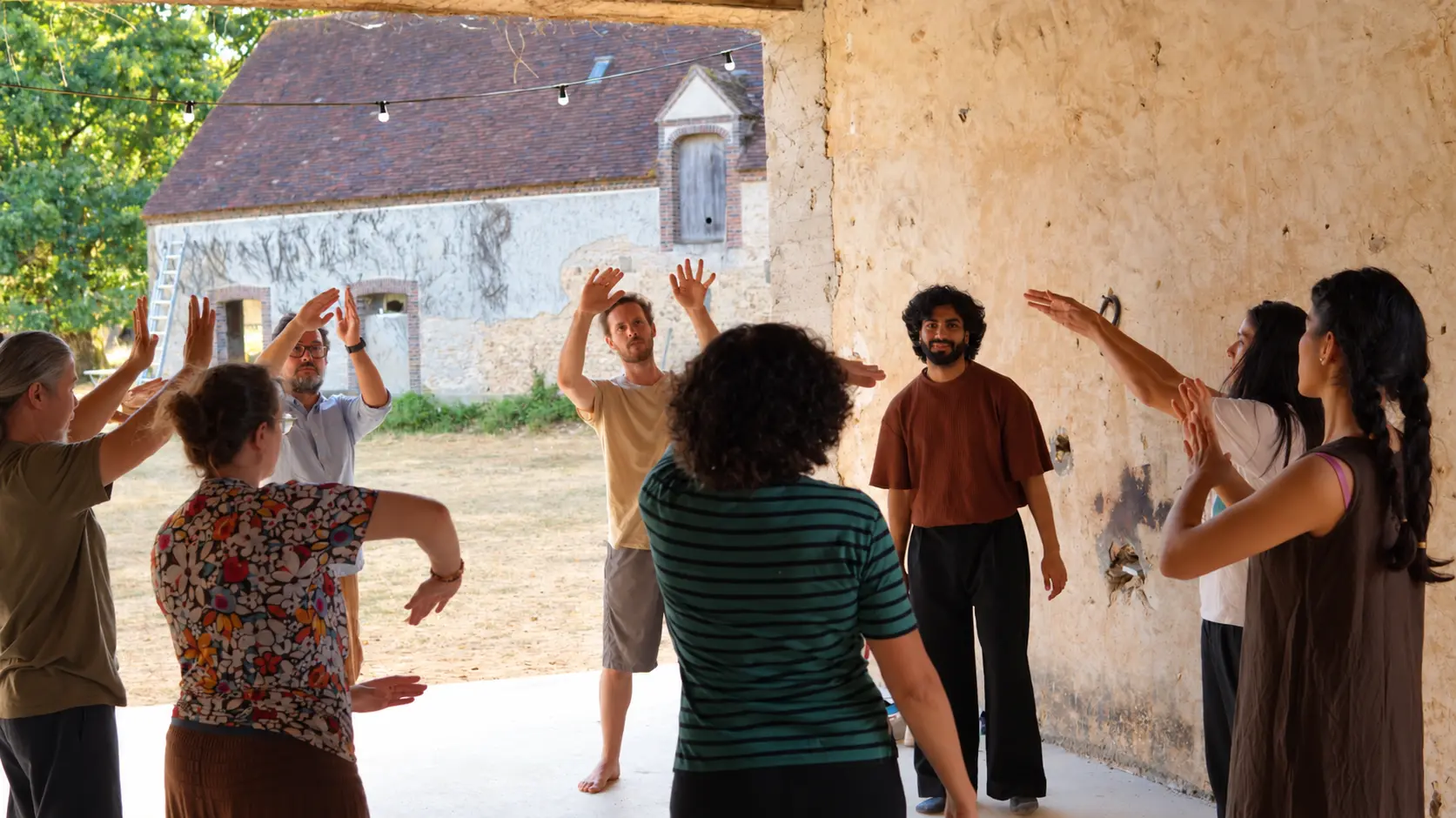 Mehfil-e-Movement participants sharing a raised-hand gesture in an open workshop space