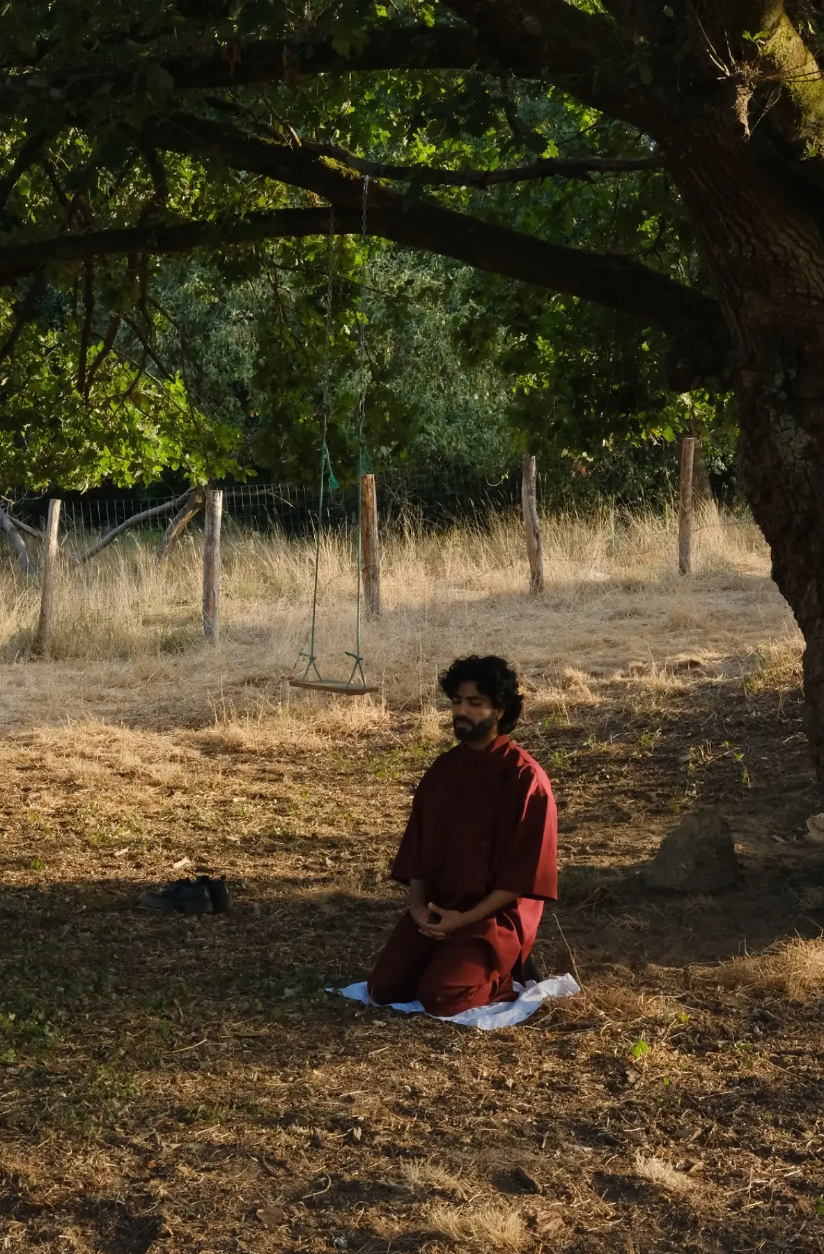 Harshit in a moment of stillness beneath a tree during an outdoor performance